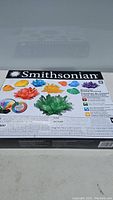 Top view of new, unopened Smithsonian Electronic Crystal Growing Kit box showing colorful images of crystals on black background.