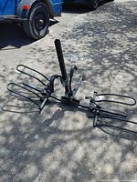 View of folded bike carrier on ground showing folding arms and vertical support for two bikes.