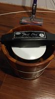 Front view of Frost King ice cream maker showing the black lid with handle and wooden bucket.