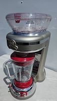Full image of Margaritaville drink mixer showing ice crusher compartment on top and glass blender jar below with red accents.