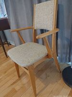Front angle view of MCM armchair showing wooden frame and beige upholstered seat and backrest