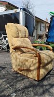 Side angle showing recliner in upright position, beige corduroy fabric, wooden armrests and recliner lever visible