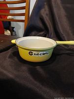 Side view of yellow Le Creuset saucepan with logo visible.