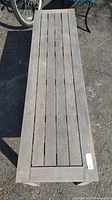 Top view showing the slatted wood surface of the bench with weathered grey wood.