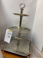 Front view of the three-tiered metal serving tray showing all three octagonal trays stacked and central handle.