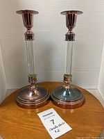 Photo of two metal and glass candlesticks with round weighted bases and clear glass stems, showing tarnish and need for cleaning.