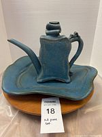 Front view of the decorative blue ceramic teapot sitting on the matching tray, showing overall shape and color.