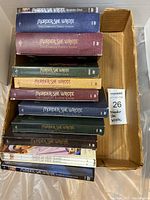 Photo of twelve boxed sets of Murder She Wrote DVD collection in various colors stacked inside a cardboard box.