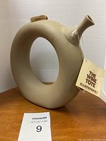 Hartstone The Wine Tote bisque ceramic wine chiller displayed on wooden surface, neutral background. Shows circular sculptural design with spout and cork stopper.