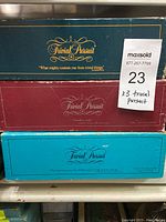 Photo showing three Trivial Pursuit game boxes stacked on top of each other. Boxes are dark green, red, and turquoise blue, each with Trivial Pursuit branding.
