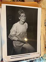 Black and white photo of a woman in eyeglasses and a sweater, seated, medium shot