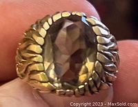 Close-up of the front of the gold ring showing the oval faceted stone and textured gold band.