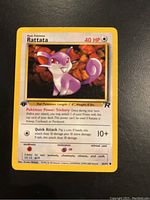 Photo of a Rattata Pokémon card 1st Edition Team Rocket with 40 HP, showing card artwork and attacks.