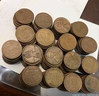 Stacks of Lincoln wheat ear pennies showing both obverse (Lincoln's profile) and reverse (wheat ears design) sides, various wear and patina states. Presence of steel pennies with distinct lighter color also visible.