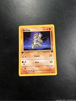 Photo of Machop Pokémon card from first edition Team Rocket set showing front face with 50 HP and fighting type moves Punch and Kick.