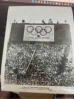 Black and white photo still showing large stadium crowd and Olympic rings with motto 'Citius Altius Fortius'. A scene from the 1948 Olympic Games film.