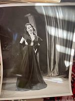 Photo of a woman in a long dark gown standing on stage with curtains in background
