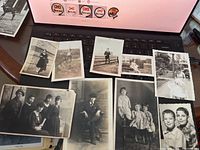 Photo showing assortment of early 1900s black and white family photos laid on keyboard, several portraits and group photos visible.