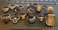 Overview of 16 sterling silver rings with various stone types and sizes arranged on a keyboard surface.