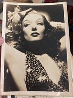 Photo of a black and white promotional headshot of a female movie star in 1940s attire with printed autograph indication