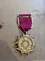 Gold star-shaped US military medal with burgundy ribbon, inscribed with 'United States of America' and 'For Military Merit'