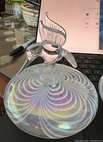 Close-up of one iridescent glass decanter with a hummingbird stopper showing the swirling pattern and iridescence.