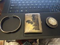 Group shot of bracelet, cigarette case and brooch on laptop