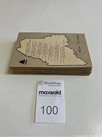 Stack of 50 postcards showing the back of one card with map outline and text referencing locations, card edges showing thickness and quantity