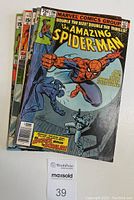 Stack of five comic books showing colorful covers, including The Amazing Spider-Man and Captain Marvel issues.