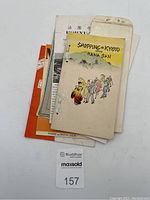 Lot of 7 Japanese brochures and envelopes stacked together showing varying sizes and colors, with 'Shopping in Kyoto with Hana San' brochure visible on top, featuring illustrated cover and tied binding.