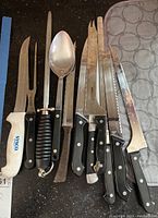 Photo of carving knives, fork, serving spoon, one handle with burn mark