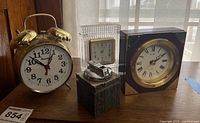 Front view of three clocks and one lighter on wooden surface