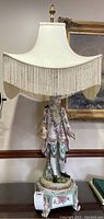 Full view of the Victorian style ceramic lamp with fringed shade showing the entire lamp height and figurative base.