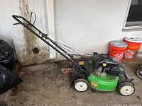 Lawn mower overall view showing green deck, black engine top, and taped damaged handle.