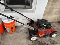 Full side view of Toro Recycler lawn mower showing red deck, black engine cover, handlebar, and wheels.
