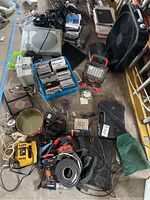 Overview of assorted workshop tools, electronics, music media, and household items including power tools and fan.