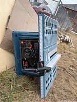 Table saw lying on its side outdoors showing the tabletop surface, adjustment handles, and control panel.