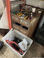 Overview photo of metal organizer chest with tools on top and plastic bin with Lasko heater and cords below.