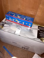 Box of Hampton Bay Windward II 54 inch ceiling fan with painted white finish and included light kit and remote control. Packaged in original box.
