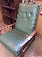 Full front view of the lounge chair showing wooden frame and green vinyl cushions