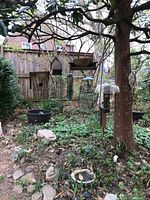 Photo of bird feeders, pots, and birdbaths hanging and on garden ground under tree
