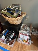 Wide view of the lot showing baskets, plastic bins filled with needlepoint kits, and craft materials.