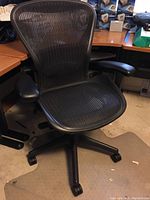 Front view of black mesh office chair on floor mat