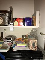 Lower shelf with assorted sticky notes, paper clips, a cup dispenser with circle design and stacks of paper