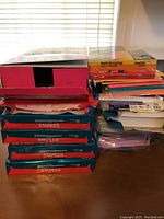 Stack of multiple reams of printer paper including Staples and other brands on a wooden surface.