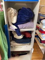 Shelf of folded bathrobes and sweaters in large and extra large sizes