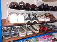 Three-level white wire rack holding various women's shoes size 7 including sandals, casual shoes, athletic and dress shoes.