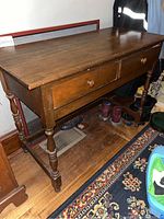 Front and side view of the wooden foyer table with two drawers and turned legs showing overall condition and shape.