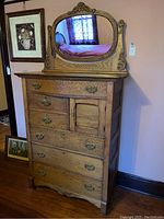 Front view of oak dresser with six drawers, hat compartment and attached oval mirror