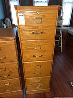 Front view of the wooden 4-drawer file cabinet showing metal handles and label holders on each drawer.